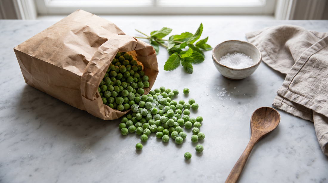 Frost-covered frozen peas on a marble counter with mint and salt, ready to cook without turning watery