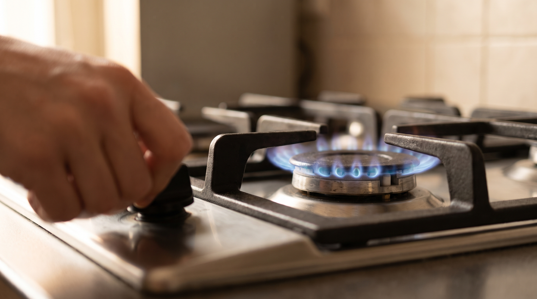 Hand turning a gas stove knob to a low blue flame, the setting to check before using a heat diffuser