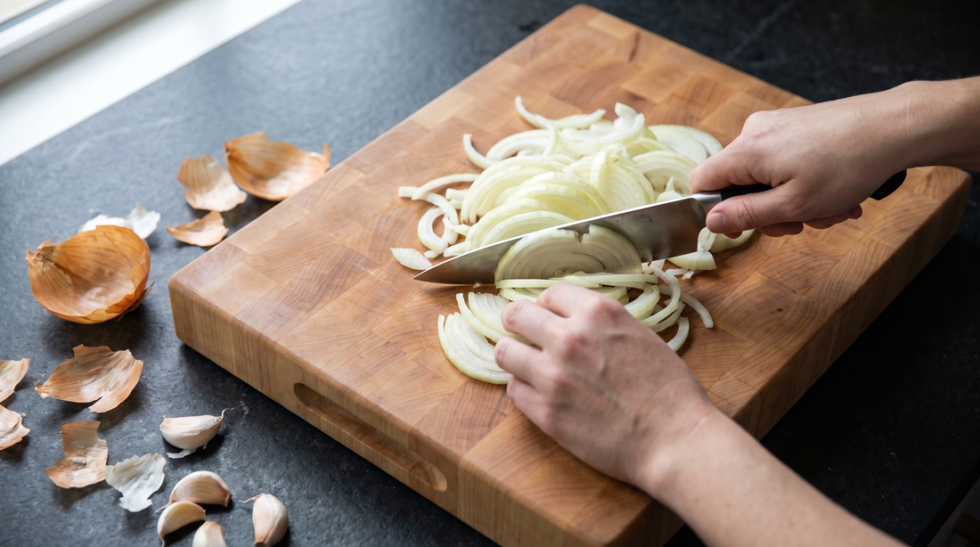 Hands slicing onions on a wooden board, the softer alternative to glass cutting boards