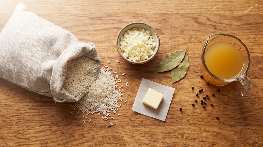 Dry long-grain rice, diced onion, butter and stock laid out for rice pilaf in a titanium pan