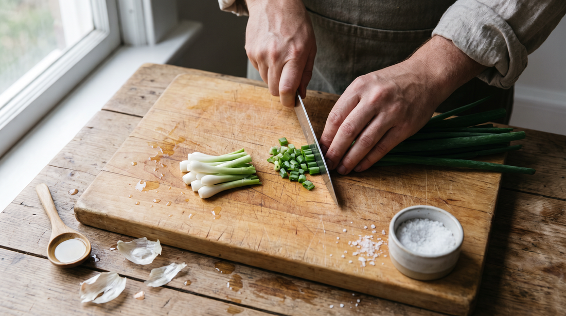 Hands cutting scallions into short pieces on a wooden board before you sear scallions for a rice bowl